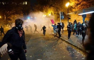 People try to move away from a gas cloud during a protest against the election of Republican Donald Trump as President of the United States in Portland, Oregon